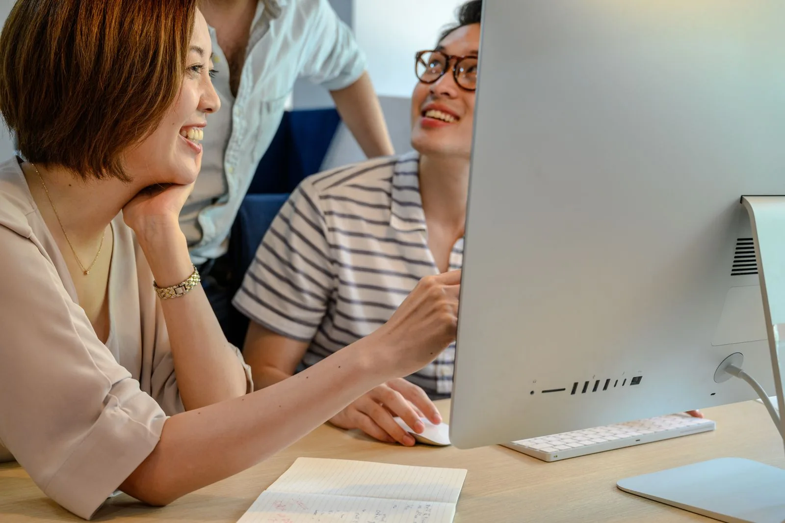 Un gruppo diversificato di colleghi che collaborano su un computer in un ambiente d'ufficio moderno.